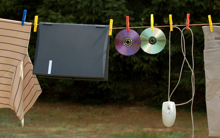 Clothes, a laptop, a mouse, and CDs hang from a clothes line to dry, representing cleaning your data. 