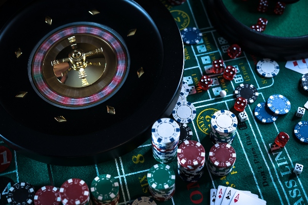 A casino table is decked out with cards, dice, and a roulette spinning table.